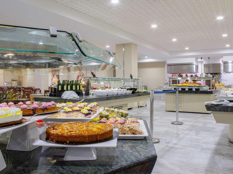 Buffet mit verschiedenen Kuchen und Torten in einem modernen, gut beleuchteten Speisesaal.