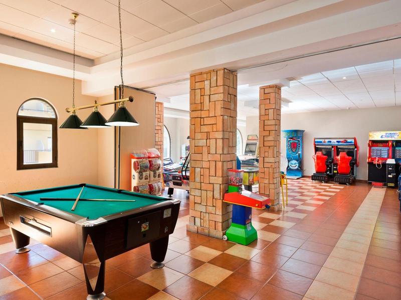 Großer Freizeitraum mit Billardtisch, Spielautomaten und farbenfrohen Sitzgelegenheiten.