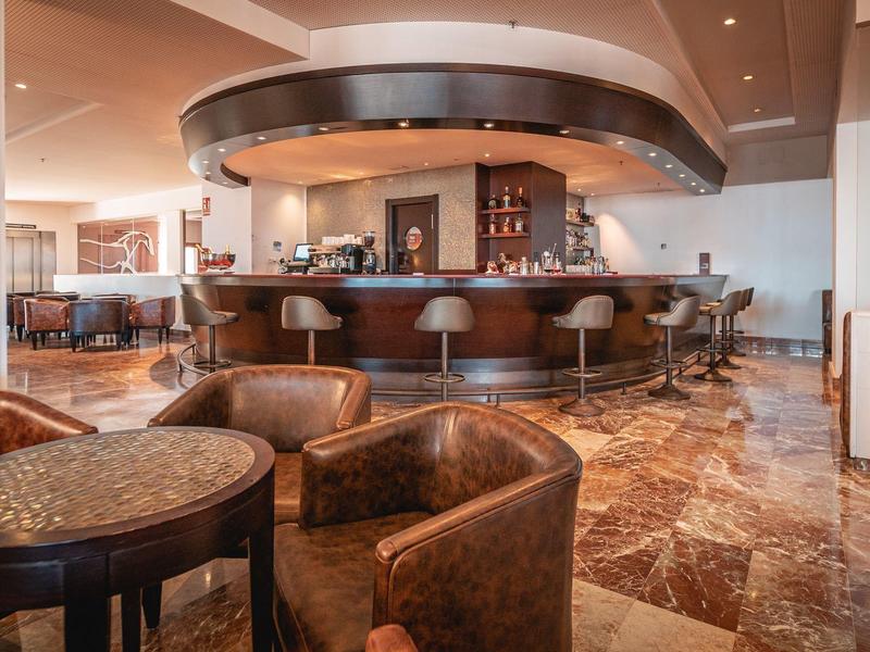 Moderner Barbereich mit braunen Ledersesseln, runder Theke und Marmorfußboden.