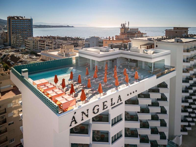 Dachterrasse mit orangenen Sonnenschirmen und Liegestühlen, Meerblick im Hintergrund.