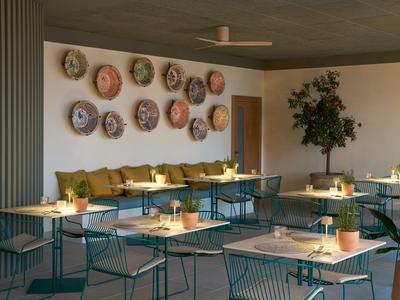 Salle à manger d'hôtel moderne avec chaises vertes, tables et assiettes murales décoratives.