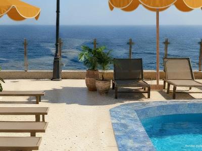 Terrazza con piscina, sdraio e ombrelloni con vista sul mare.