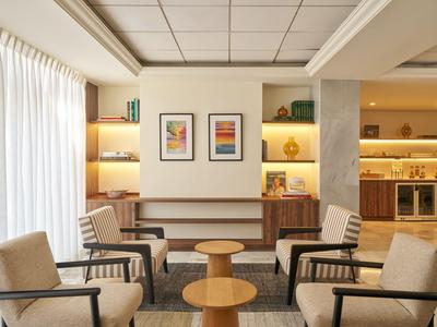 Hall d'hôtel moderne avec des chaises, tables et éléments décoratifs.