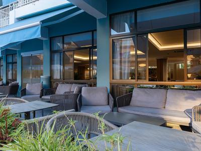 Area terrazza hotel moderna con sedute comode, tavoli e illuminazione elegante.