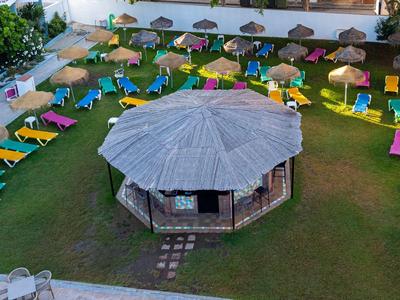 Un'area erbosa con lettini colorati e ombrelloni attorno a un padiglione rotondo centrale.