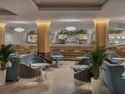 Elegante area lounge dell'hotel con poltrone comode, piante e illuminazione calda.