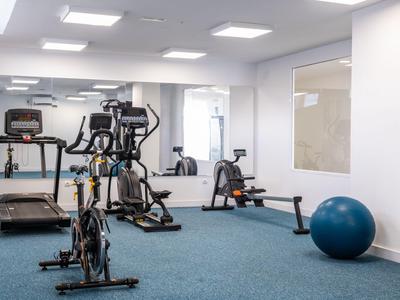 Moderner Fitnessraum mit Laufband, Fahrrädern und Gymnastikball im Hotel.