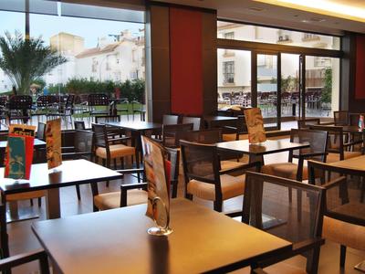 Pusty obszar restauracyjny z nowoczesnymi stołami i krzesłami oraz dużą szklaną ścianą z widokiem na taras.