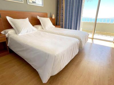 Nowoczesny pokój hotelowy z dwoma łóżkami pojedynczymi i balkonem z widokiem na morze.