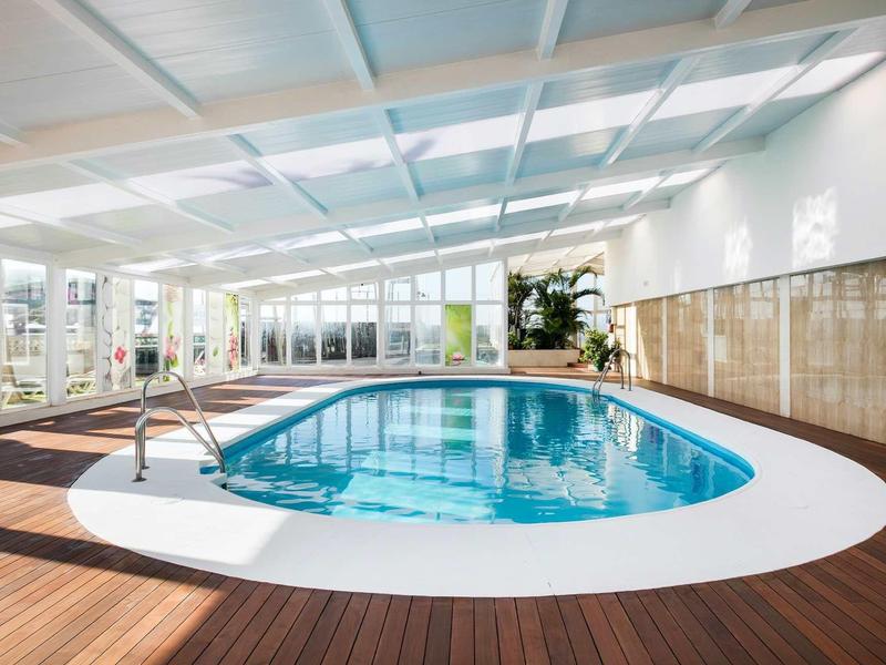 Moderner Innenpool mit Holzboden, weißen Wänden und viel Tageslicht durch große Fenster.