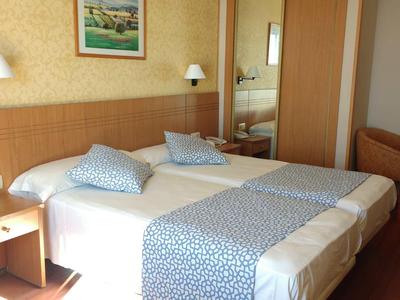 Hotel room with two beds, nightstand, lamps, and carpet flooring