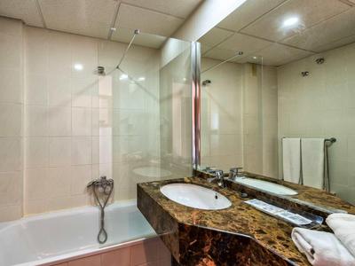 Modern bathroom with bathtub, large mirrors, and marble countertop.