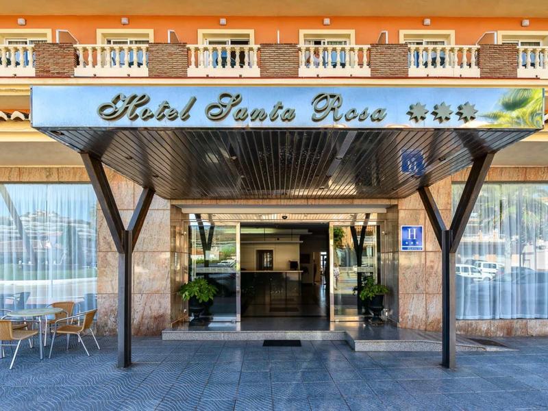 Eingang des Hotel Santa Rosa mit überdachtem Vordach, Sitzgelegenheiten und hellen Fassadentönen.