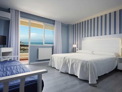 Habitación de hotel con cama doble, televisor y balcón con vista al mar.