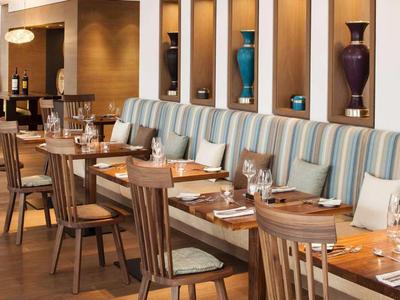 Modernes Restaurant mit Holztischen, Stühlen und gestreifter Sitzbank an der Wand.