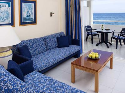 Wohnzimmer mit blauen Sofas, Holztisch und Balkon mit Meerblick.