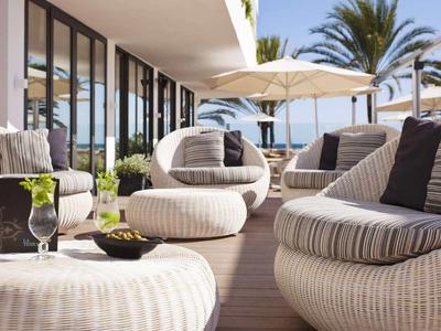 Gemütliche Lounge auf der Hotelterrasse mit bequemen Sesseln und Sonnenschirmen bei sonnigem Wetter.