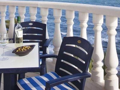 Balkon mit Tisch, zwei Stühlen und Meeresblick im Hintergrund.