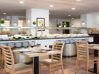 Moderní snídaňová část s bufetem a dřevěnými stoly v hotelu.