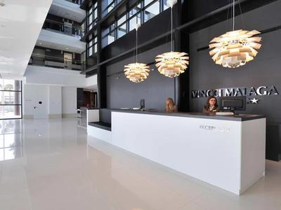 Moderner Hotel-Lobby-Empfangsbereich mit weißem Tresen und dekorativen Pendelleuchten.