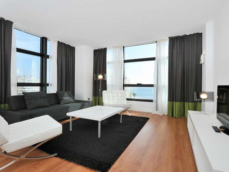 Moderner Wohnraum mit großen Fenstern, schwarzem Teppich, weißem Sofa und Holzfußboden.