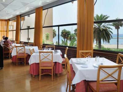 Elegantes Restaurant mit weiß gedeckten Tischen und Meerblick durch große Fenster.