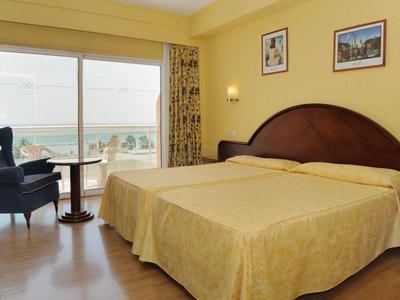 Helles Hotelzimmer mit Doppelbett, Balkon und Meerblick.