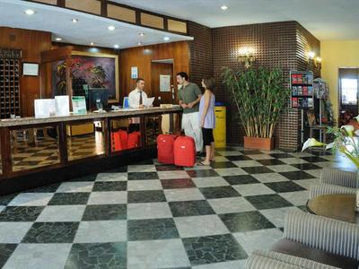 Hotelrezeptionsbereich mit einem Gast und zwei Mitarbeitern am Empfangstresen