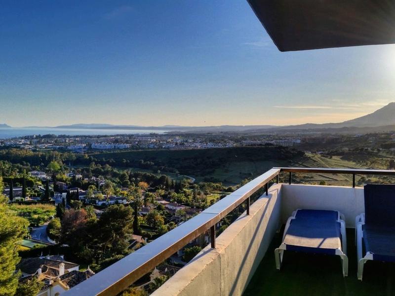 Balkon mit Stühlen, Blick auf Stadt, Bäume, Hügel und Sonnenaufgang am klaren Himmel.
