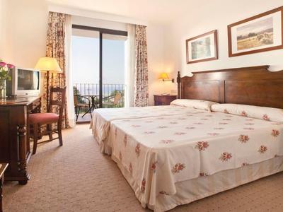 Gemütliches Schlafzimmer mit Doppelbett, Holzmöbeln und Balkon mit Blick ins Freie.