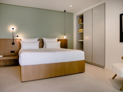 Modernes Schlafzimmer mit großem Bett, weißen Wänden, eingebautem Schrank und minimalistischer Dekoration.