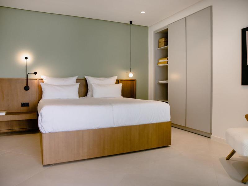 Modernes Schlafzimmer mit großem Bett, weißen Wänden, eingebautem Schrank und minimalistischer Dekoration.