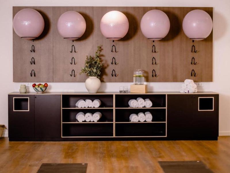 Moderne Umkleide mit Holzboden, schwarzen Schränken, großen rosa Bällen und Handtüchern.