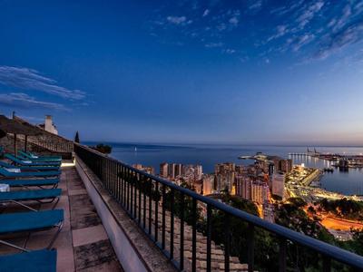 Balkon mit Liegestühlen und Meerblick bei Dämmerung in der Stadt am Hafen