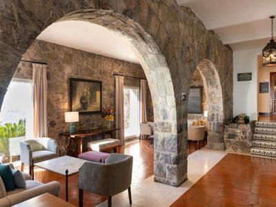 Wnętrze hotelu z kamiennymi łukami, meblami wypoczynkowymi i vintage dekoracją w ciepłym świetle.