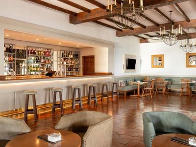 Elegancki bar hotelowy z drewnianym sufitem, stołkami barowymi i miejscami do siedzenia.