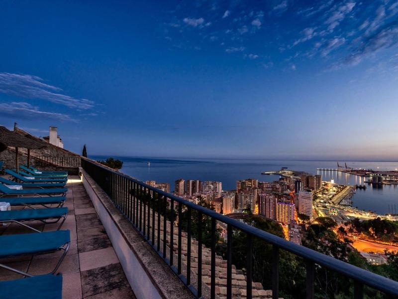 Balkon mit Liegestühlen und Meerblick bei Dämmerung in der Stadt am Hafen