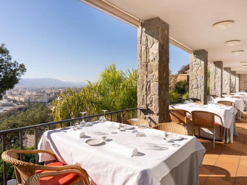 Terrasse mit gedeckten Tischen und Blick auf die Stadt und Berge bei klarem Himmel