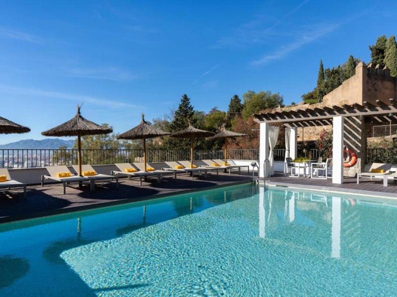 Moderner Poolbereich mit Liegestühlen und Sonnenschirmen unter klarem blauem Himmel.