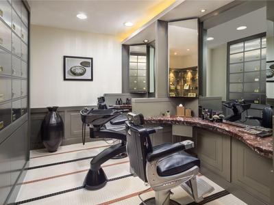 Modern eingerichteter Friseursalon mit schwarzen Sesseln und großem Spiegel.