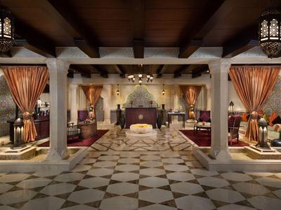 Luxuriöse Hotellobby mit Mosaikboden, dekorativen Vorhängen, Holzdecken und warmem Licht.