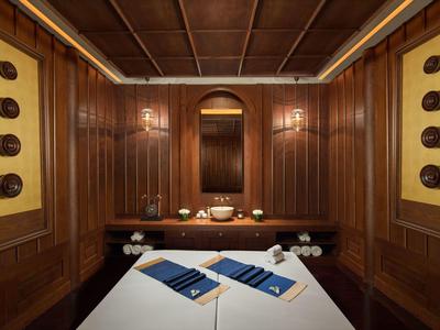 Schlicht eingerichteter Massageraum mit Holzwänden, Decke und weißen Behandlungsbetten.