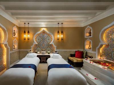 Luxuriöser Wellnessraum mit orientalischem Design, zwei Massageliegen und warmem Licht.