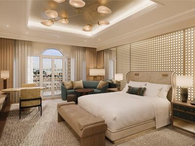 Geräumiges Hotelzimmer mit großem Bett, Sofa, Schreibtisch und Balkon mit Blick auf Stadt.