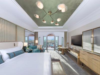 Modernes Hotelzimmer mit großem Bett, Sitzbereich und Balkon mit Meerblick.