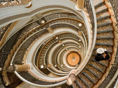 Spiralformige Treppe mit verzierter Geländerstruktur, Blick von oben nach unten.