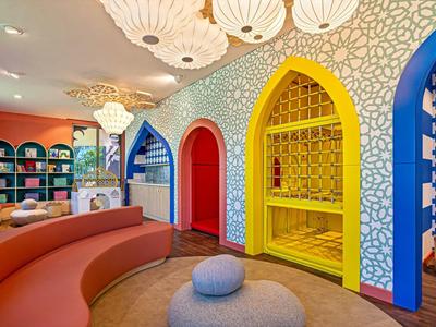 Bunt eingerichteter Hotel-Loungebereich mit geschwungenem Sofa und dekorativen Wandnischen.