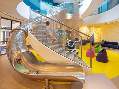 Innenbereich mit Rutsche, Sitzsäcken und moderner Inneneinrichtung in einem Hotel oder Freizeitbereich.