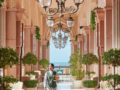 Luxuriöser Gang mit Lampen, Pflanzen und Blick auf das Meer in einem Hotel.