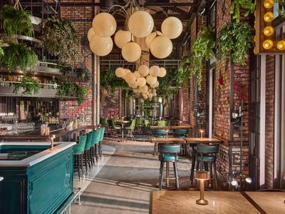 Modernes Restaurant mit grünen Stühlen, Holztischen und vielen Pflanzen an der Decke